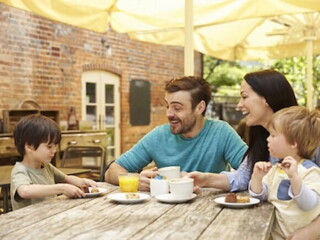 Una familia y dos niños felices sentados en la mesa